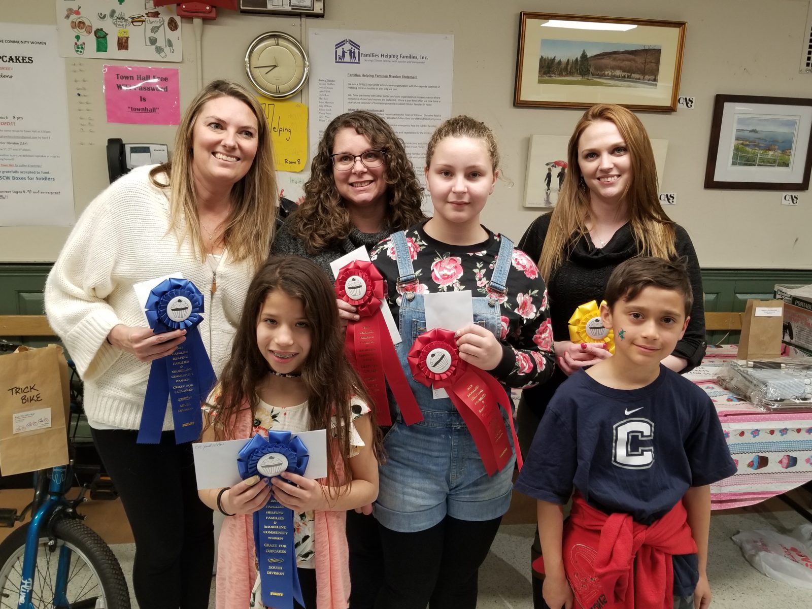 Group of people smiling with award ribbons in hand.