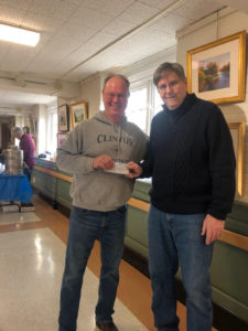 Two people standing together holding check.