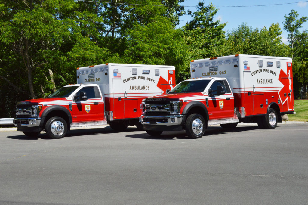 Two red and white ambulances parked outdoors.