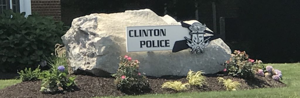 Clinton Police sign on rock with flowers.