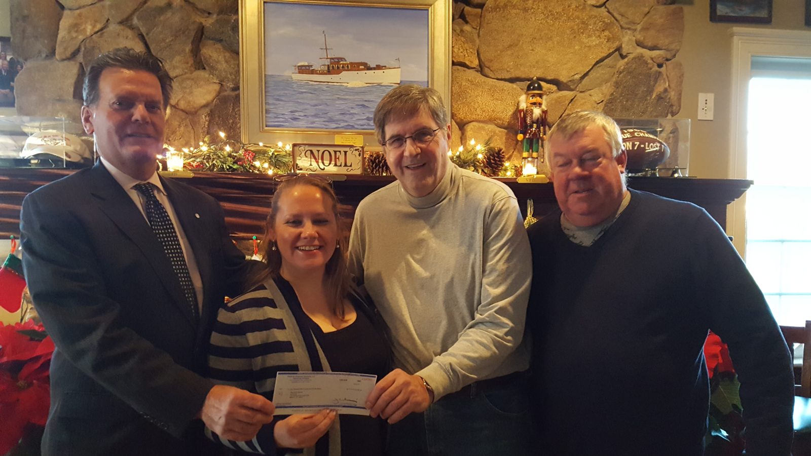 Three people smiling indoors, holding a check.